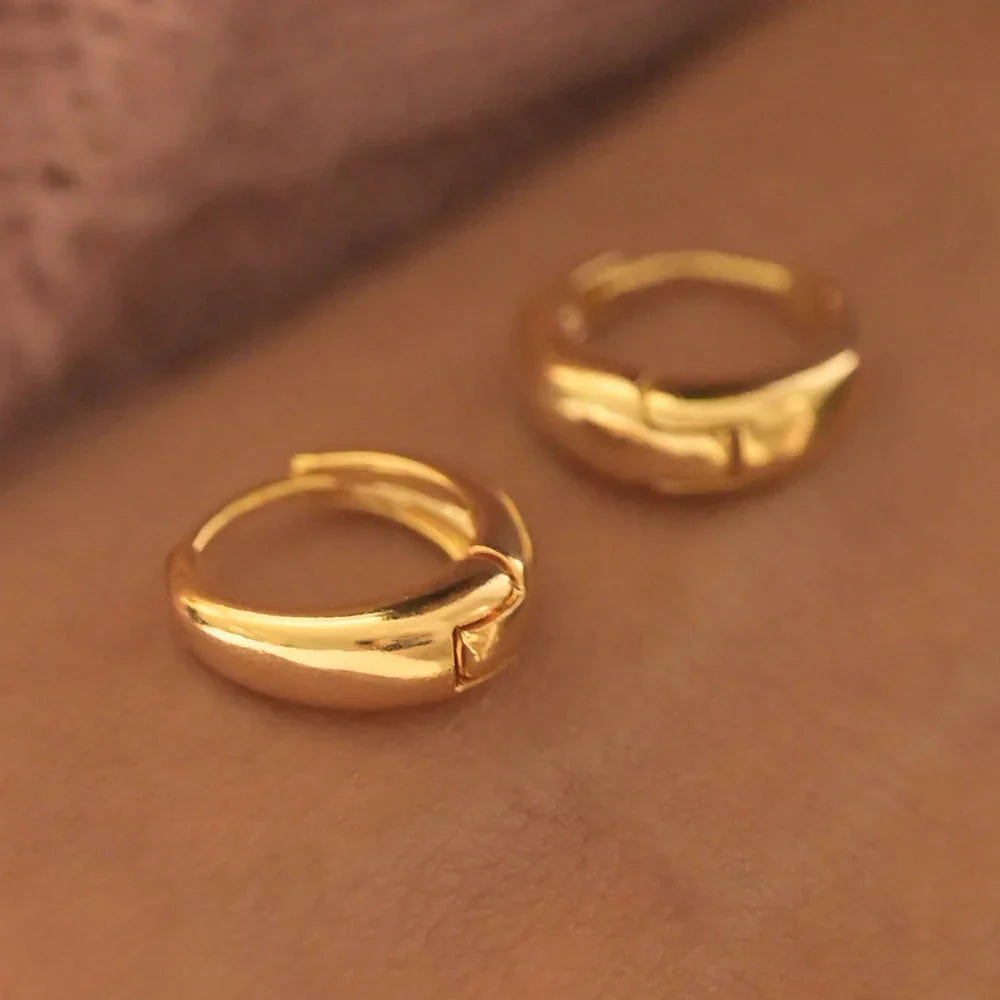 Pair of gold hoop earrings on a brown surface