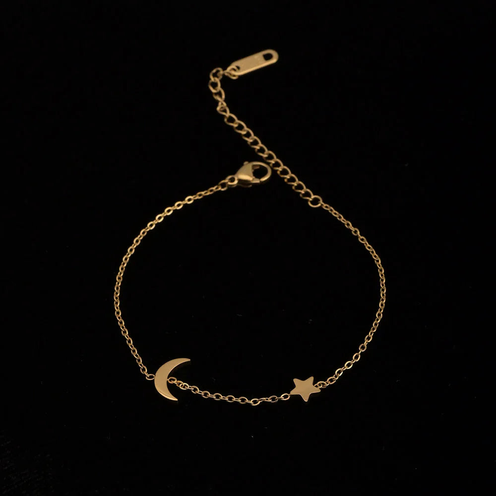 Gold bracelet with moon and star charms on a black background