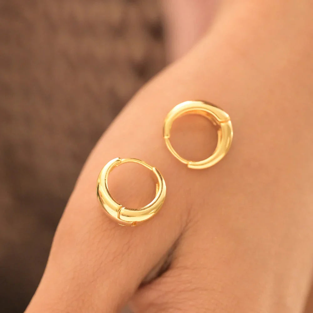 Gold hoop earrings on a person's earlobe with a blurred background