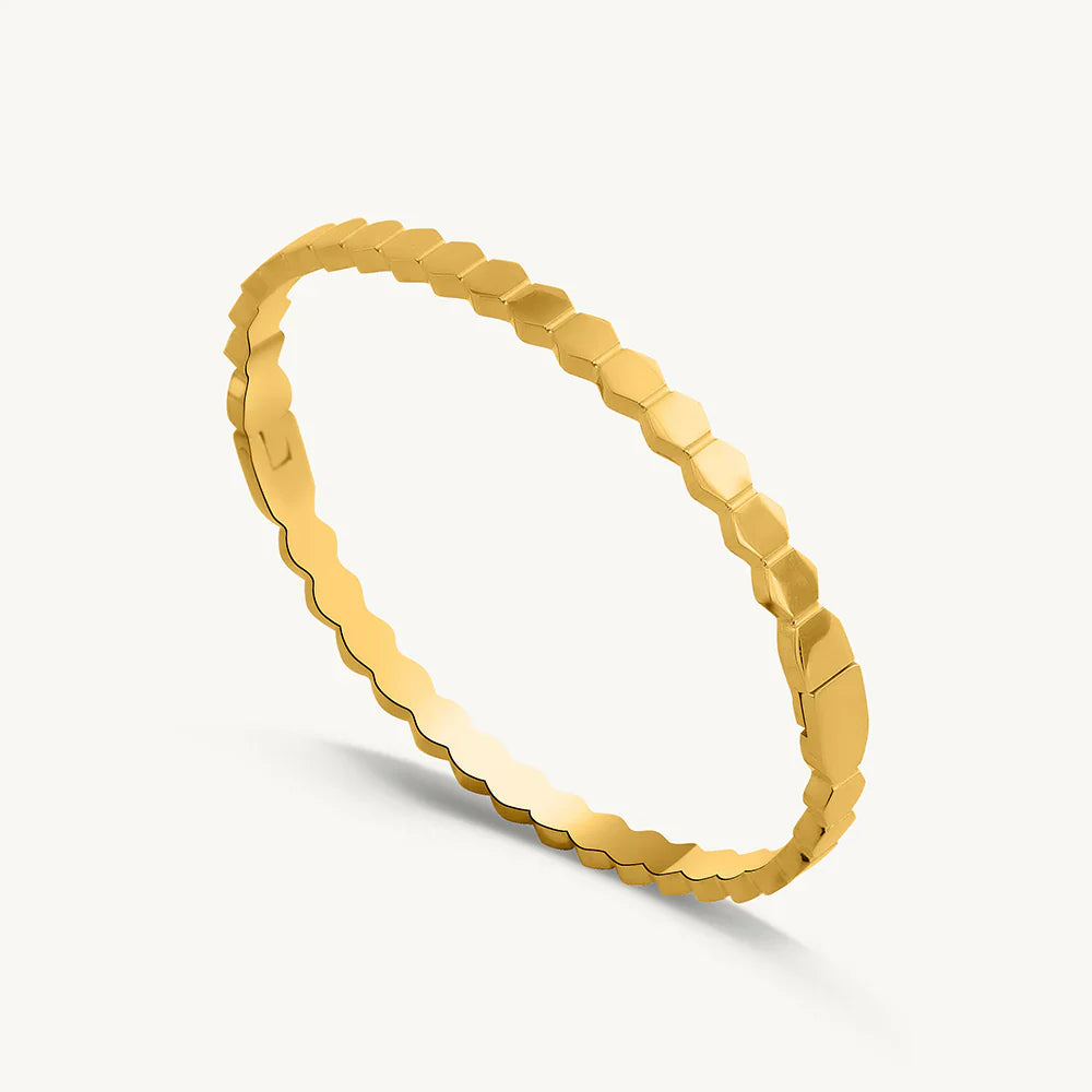 Gold bracelet with a textured pattern on a light gray background