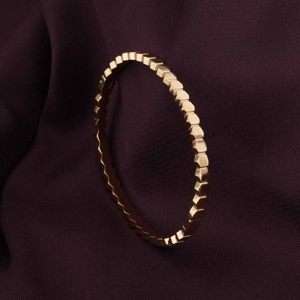Gold bracelet on a dark purple fabric background