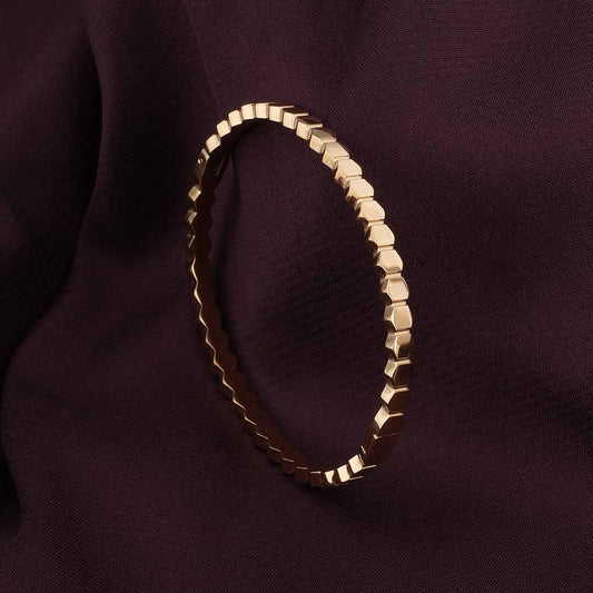 Gold bracelet on a dark purple fabric background
