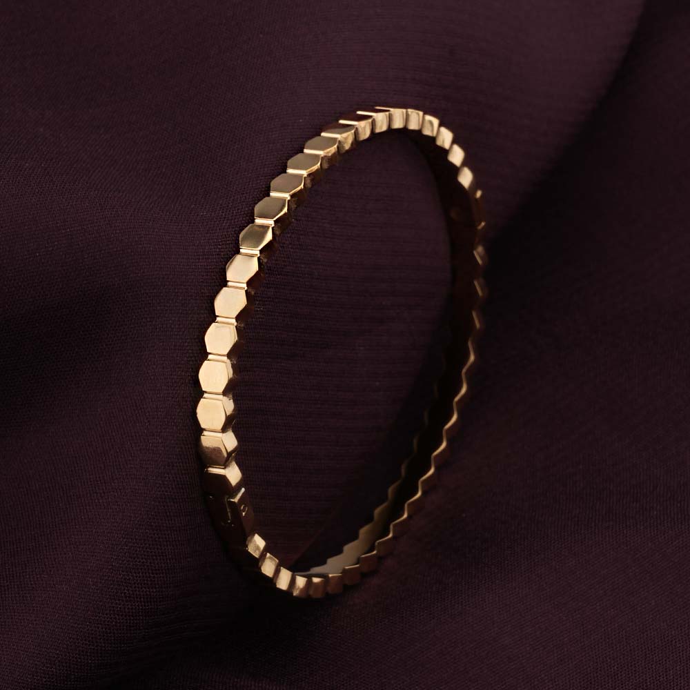 Gold hexagonal bracelet on a dark purple fabric background