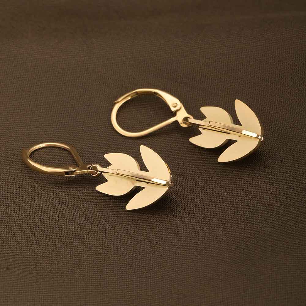 Gold leaf-shaped earrings on a brown background