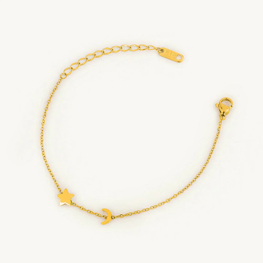 Gold bracelet with star and moon charms on a white background